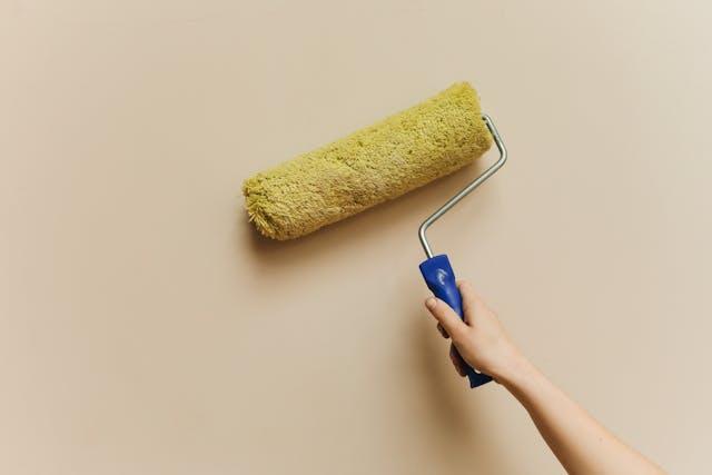 a person painting a wall with a paint roller
